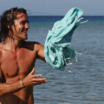 An AFL fan holds Hammamas Turkish Cotton Towel in the beach.